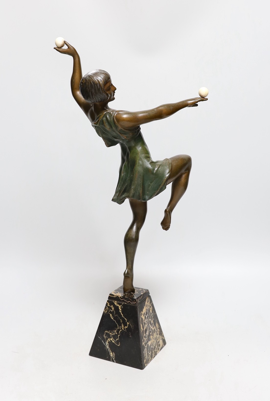 A French Art Deco patinated bronzed spelter dancer, holding two ivory spheres, on marble base, attributed to J. Limousin, 44cms high